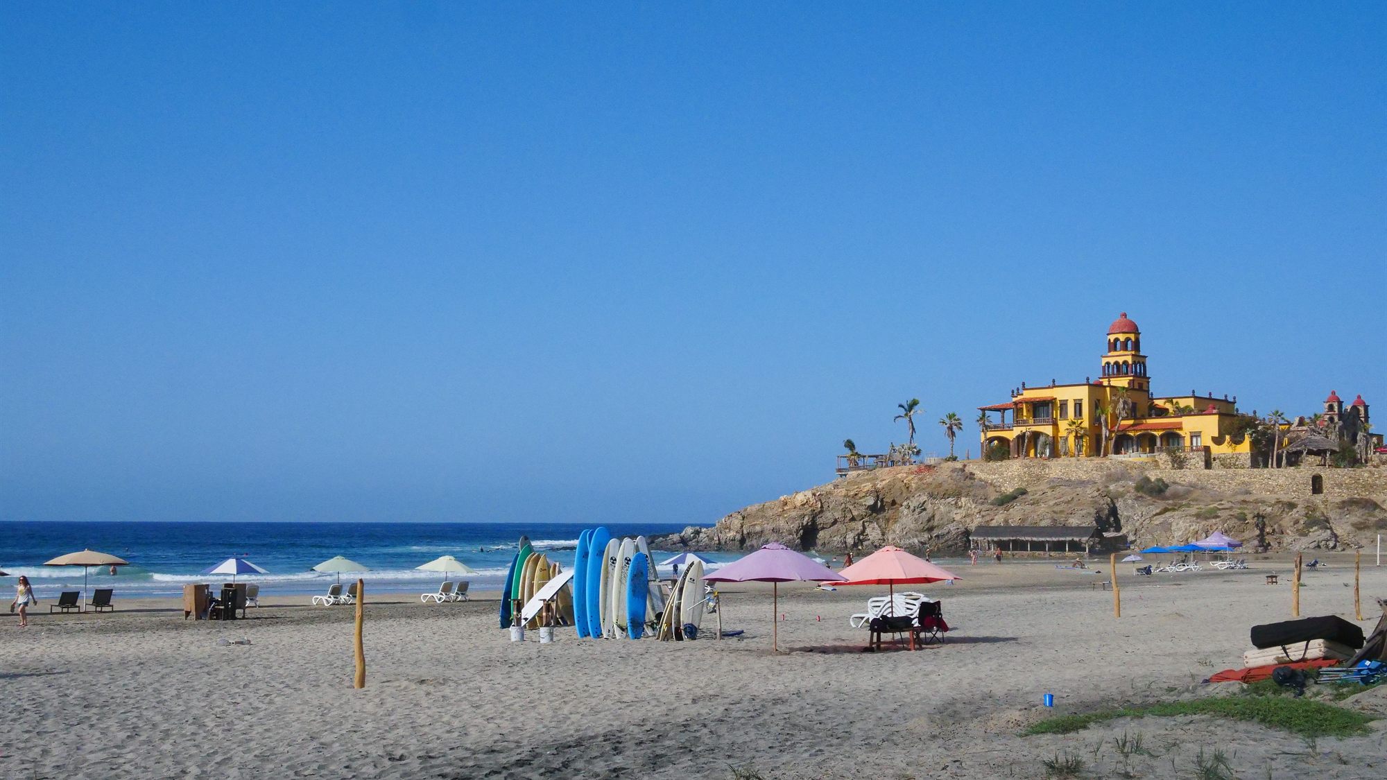 Playa abierta con tablas de surf al pie del agua.